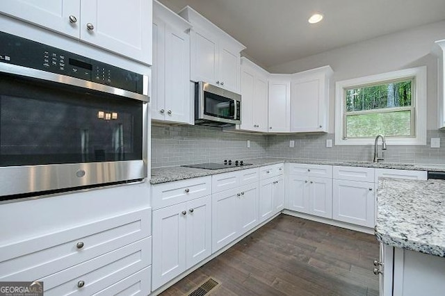 kitchen featuring decorative backsplash, appliances with stainless steel finishes, light stone counters, sink, and white cabinetry