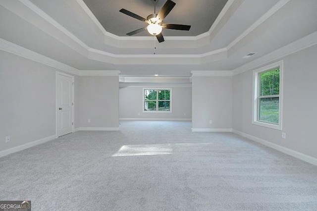 unfurnished room featuring ceiling fan, light colored carpet, crown molding, and a tray ceiling