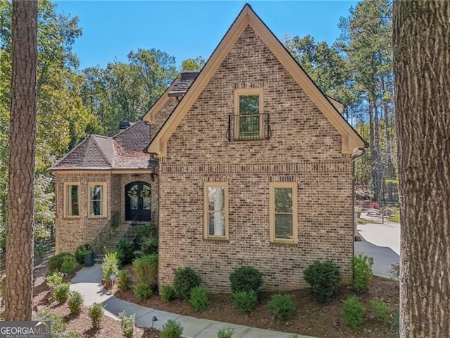 view of front of house with brick siding and roof with shingles