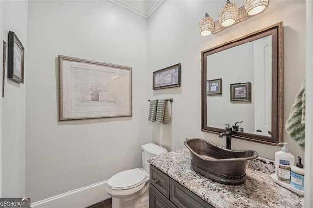 bathroom with toilet, ornamental molding, vanity, and baseboards