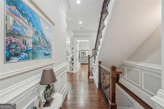 hall featuring dark wood finished floors, recessed lighting, a decorative wall, ornamental molding, and wainscoting