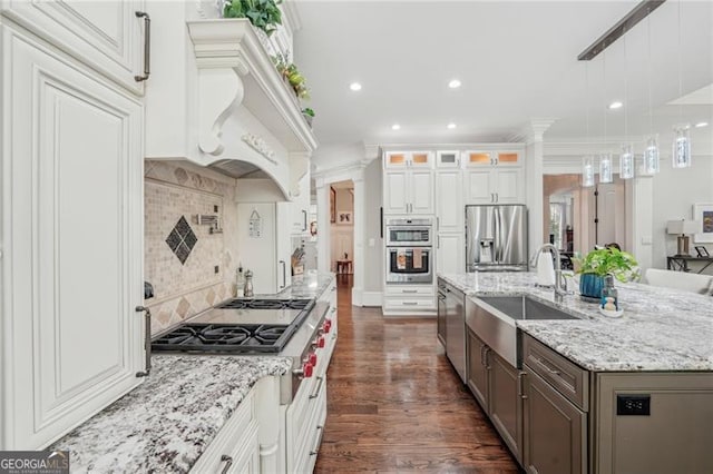 kitchen with decorative light fixtures, a center island with sink, glass insert cabinets, appliances with stainless steel finishes, and white cabinets