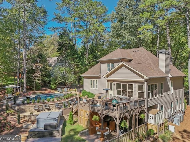 rear view of property with a chimney, an outdoor pool, and a deck