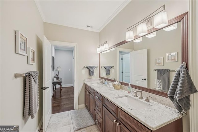 full bath featuring double vanity, ornamental molding, and a sink