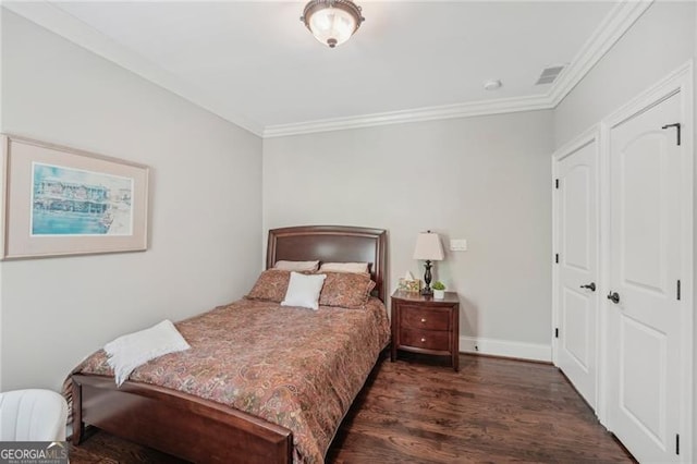 bedroom featuring baseboards, dark wood finished floors, visible vents, and crown molding