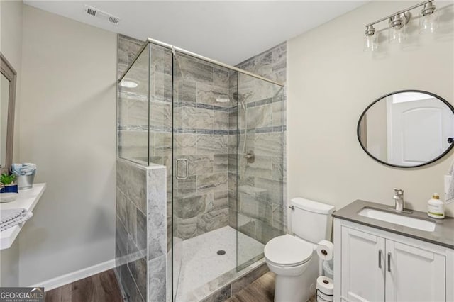 bathroom with a stall shower, baseboards, visible vents, toilet, and vanity