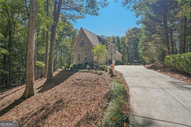 view of side of home with stone siding and driveway