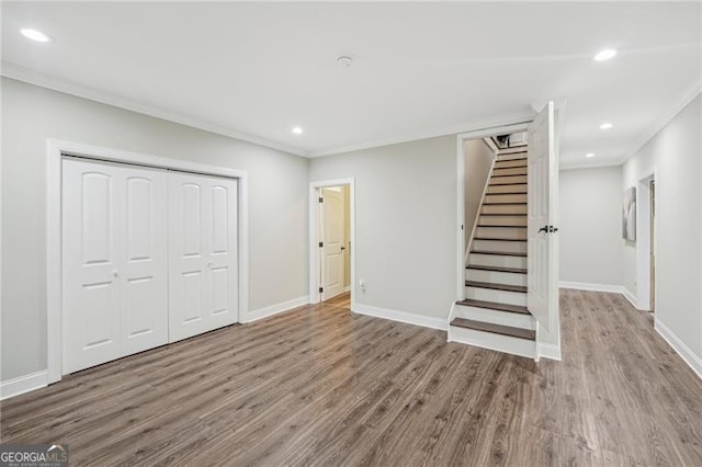 below grade area with recessed lighting, wood finished floors, baseboards, stairs, and crown molding