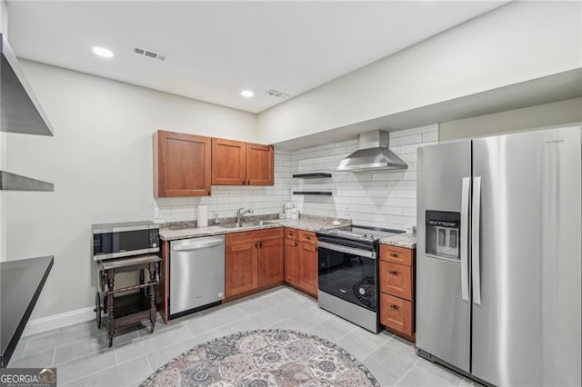 kitchen featuring visible vents, decorative backsplash, appliances with stainless steel finishes, wall chimney range hood, and a sink