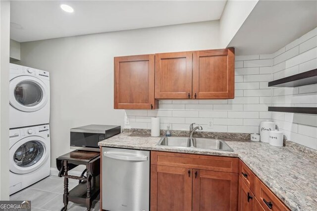 interior space with stainless steel appliances, a sink, stacked washing maching and dryer, open shelves, and tasteful backsplash