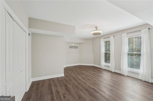 spare room with dark wood finished floors and baseboards