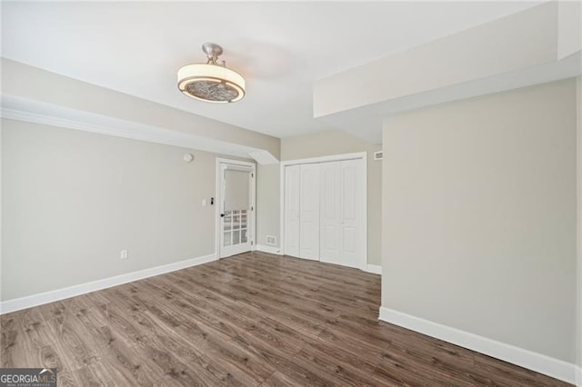 spare room with dark wood-style flooring and baseboards