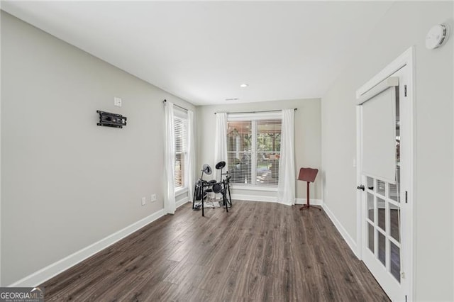 unfurnished room with dark wood-style flooring and baseboards