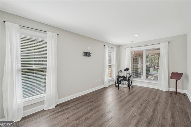 unfurnished room with dark wood-type flooring and baseboards