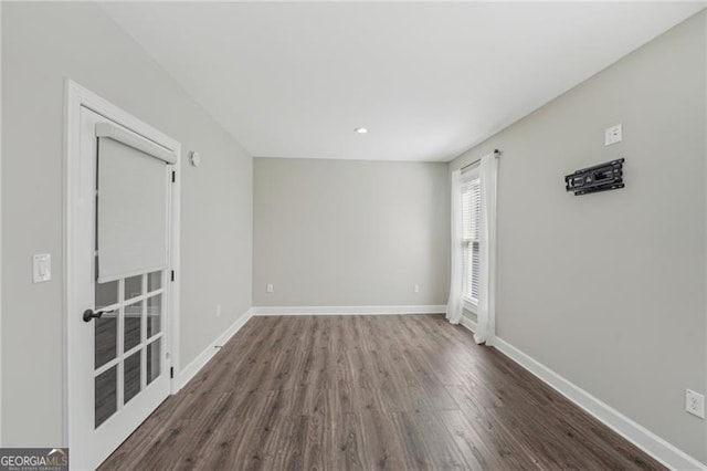 unfurnished room with baseboards and dark wood-type flooring