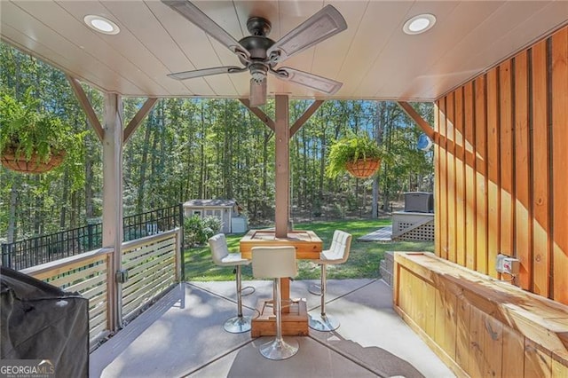 view of patio / terrace with a storage unit, area for grilling, a ceiling fan, fence, and an outdoor structure