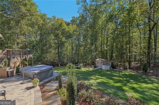 view of yard featuring a hot tub, a wooden deck, a storage shed, and a patio area