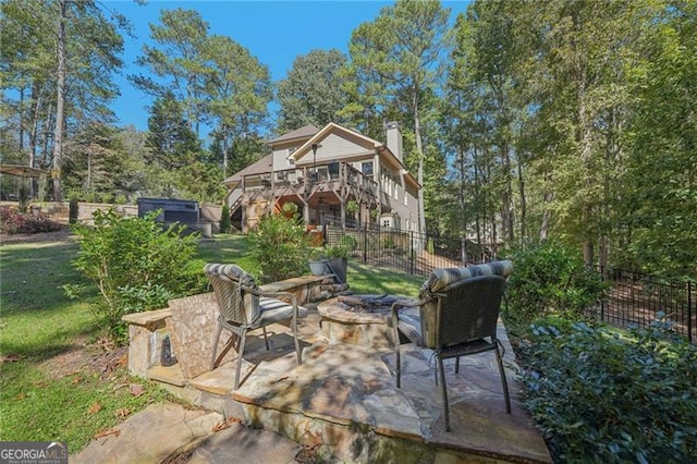 view of patio with a fire pit, a deck, and fence