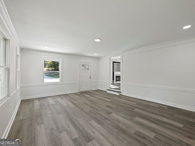 unfurnished living room featuring crown molding and dark wood-type flooring