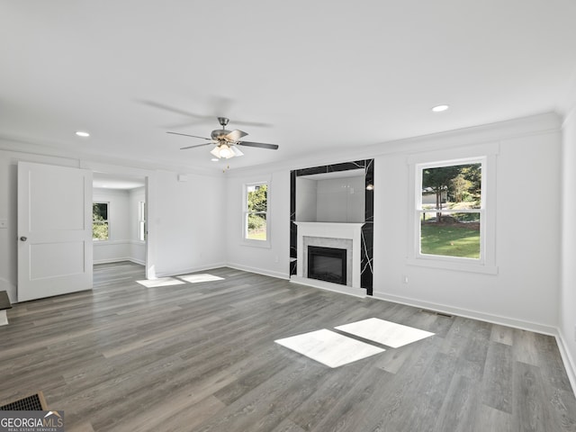 unfurnished living room featuring hardwood / wood-style flooring, ceiling fan, and crown molding