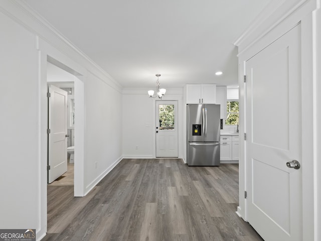 interior space featuring stainless steel fridge, white cabinets, light wood-type flooring, and ornamental molding