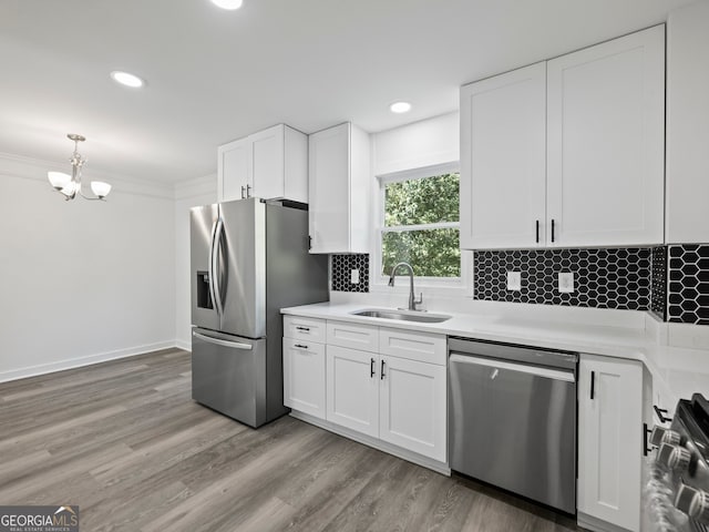 kitchen featuring backsplash, white cabinets, sink, light wood-type flooring, and appliances with stainless steel finishes