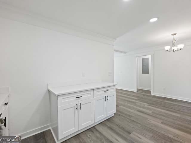 interior space with hardwood / wood-style floors, a notable chandelier, crown molding, and electric panel