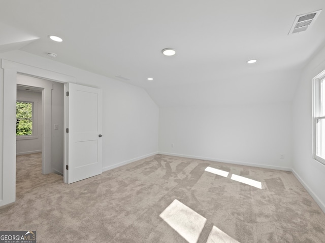 additional living space featuring lofted ceiling and light carpet