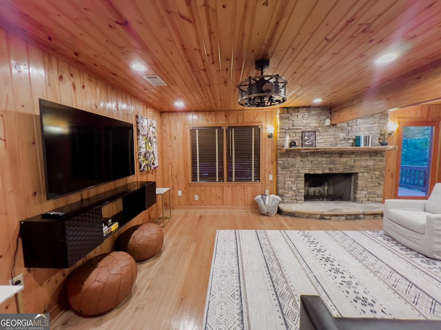 living room featuring light hardwood / wood-style flooring, wooden walls, wooden ceiling, and a fireplace