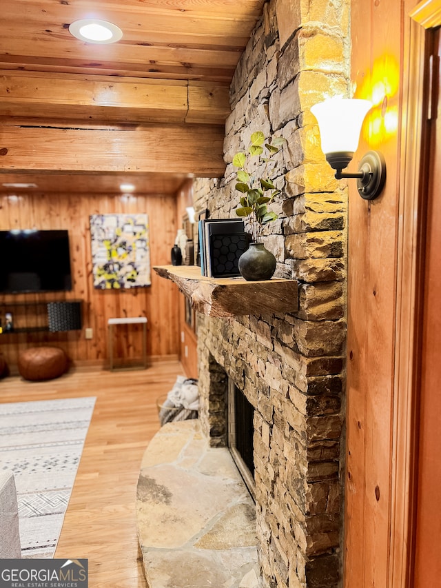 interior space featuring wooden walls, a stone fireplace, hardwood / wood-style flooring, and wooden ceiling