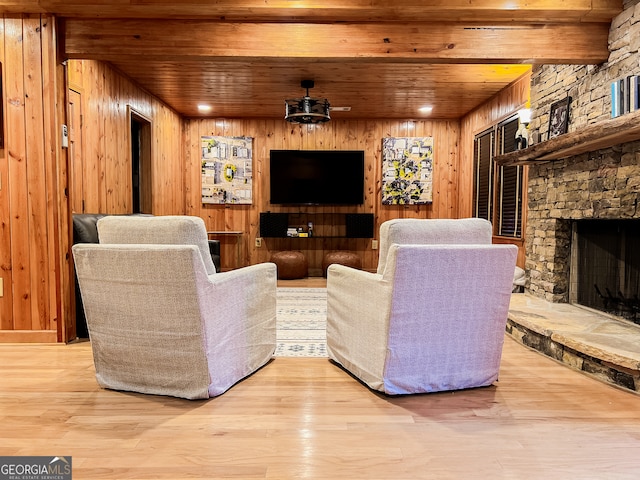 living room featuring wooden walls, wood ceiling, a fireplace, and light wood-type flooring