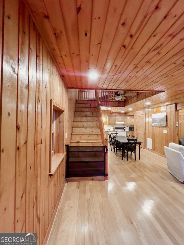 interior space with light wood-type flooring, wooden ceiling, and wooden walls