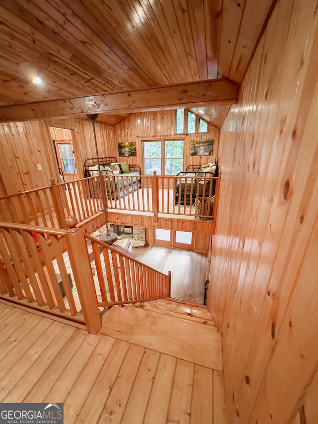 staircase featuring hardwood / wood-style floors, lofted ceiling with beams, wood ceiling, and wooden walls