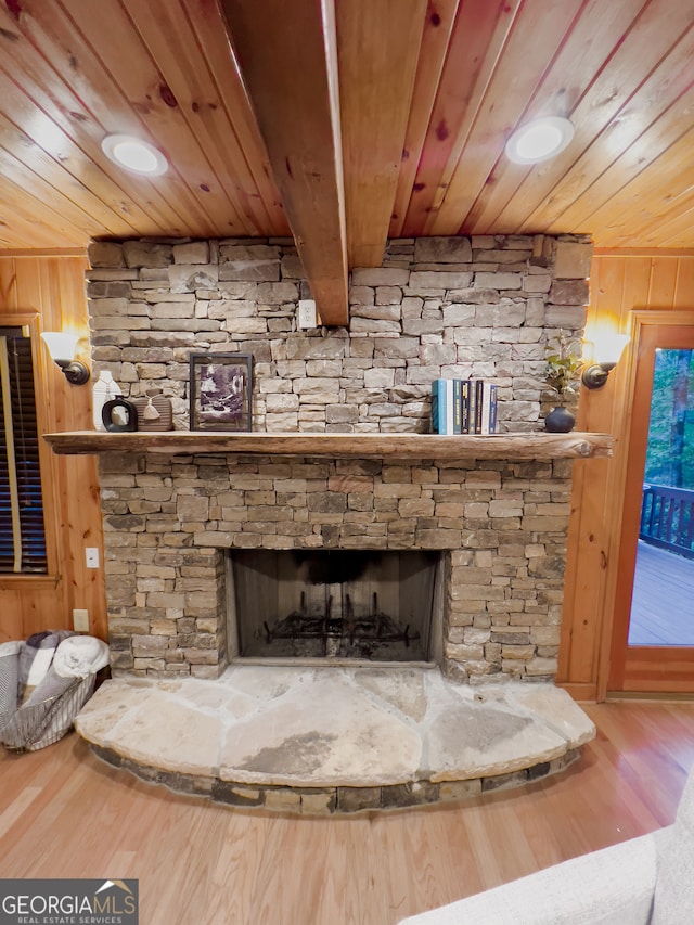 interior details with beam ceiling, wood-type flooring, wooden ceiling, a fireplace, and wooden walls