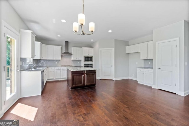 kitchen with white cabinets, a chandelier, a center island, stainless steel appliances, and wall chimney range hood