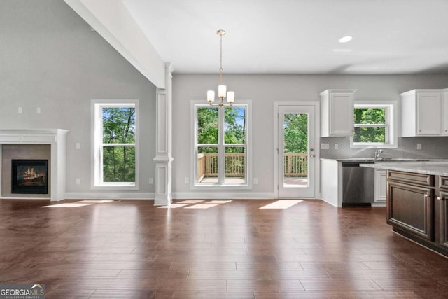 kitchen featuring white cabinets, backsplash, hanging light fixtures, stainless steel dishwasher, and a notable chandelier