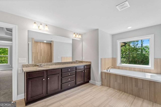 bathroom with vanity and a relaxing tiled tub