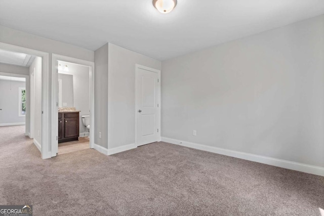 unfurnished bedroom featuring ensuite bath and light colored carpet