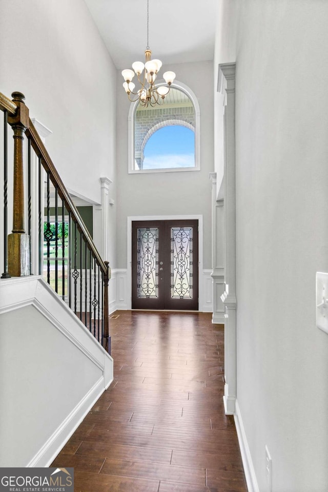 entryway featuring dark hardwood / wood-style flooring, french doors, a chandelier, and a high ceiling