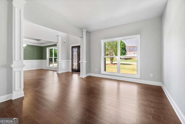 unfurnished living room with decorative columns and dark hardwood / wood-style floors