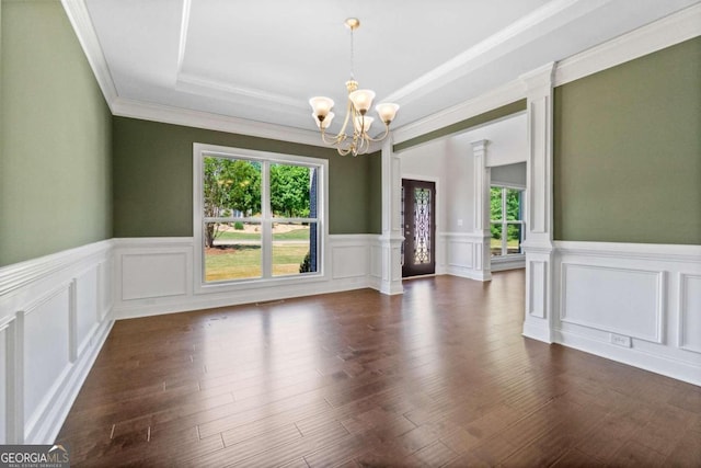 unfurnished room with a raised ceiling, dark hardwood / wood-style flooring, ornamental molding, and an inviting chandelier