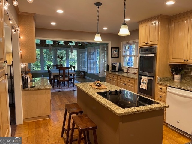 kitchen featuring white dishwasher, a center island, double oven, black electric cooktop, and light hardwood / wood-style floors