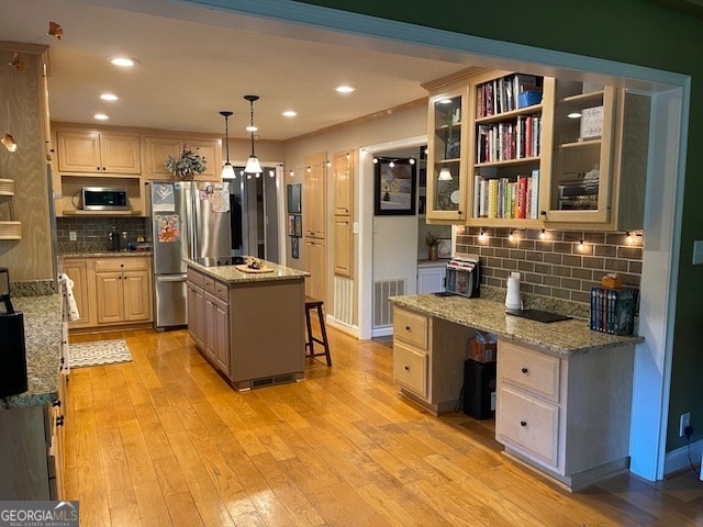 kitchen featuring a kitchen island, a breakfast bar, light stone countertops, appliances with stainless steel finishes, and light hardwood / wood-style floors