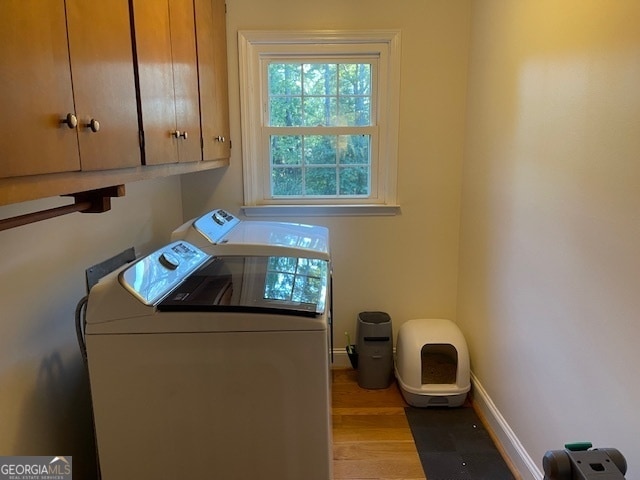 laundry area featuring light hardwood / wood-style flooring, cabinets, and washing machine and clothes dryer