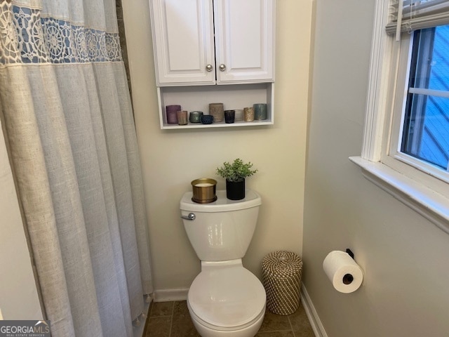 bathroom with a healthy amount of sunlight, tile patterned floors, and toilet