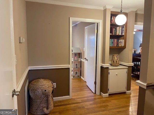 corridor with light hardwood / wood-style floors and ornamental molding