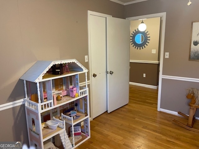 rec room with wood-type flooring and ornamental molding