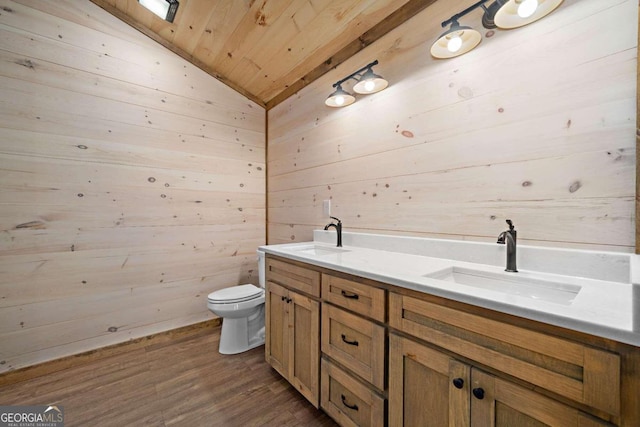 bathroom with hardwood / wood-style floors, toilet, vaulted ceiling, wooden walls, and vanity