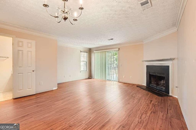 unfurnished living room with ornamental molding, a notable chandelier, a textured ceiling, and light wood-type flooring