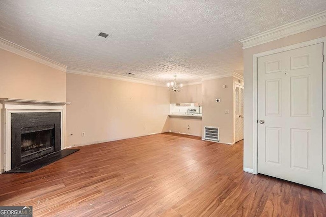 unfurnished living room with crown molding, wood-type flooring, a textured ceiling, and a chandelier